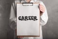 Woman holding clipboard with word CAREER on background, closeup