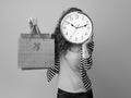 Woman holding clock in front of face and showing shopping bags Royalty Free Stock Photo