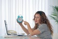 Woman holding a clock. Red-haired woman holds an alarm clock in her hand in the workplace