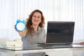 Woman holding a clock. Red-haired woman holds an alarm clock in her hand in the workplace