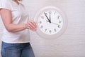 Woman holding clock showing five minutes to twelve, deadline and urgent work concept Royalty Free Stock Photo