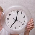 Woman holding clock showing 7 am in the morning, punctuality and discipline concept Royalty Free Stock Photo