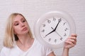 Woman holding clock showing 7 am in the morning, punctuality and discipline concept