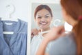 woman holding clothing on hangar and looking in mirror