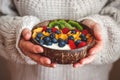 Woman holding coconut bowl with yogurt, corn flakes, sliced kiwi and berry fruit Royalty Free Stock Photo