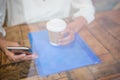 Woman holding coffee cup and mobile phone seen through cafe window Royalty Free Stock Photo