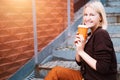 Woman holding coffee in disposable orange cup.