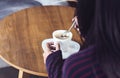 A woman holding coffee spoon and stirring hot coffee, in cafe