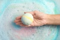 Woman holding color bath bomb over foam Royalty Free Stock Photo