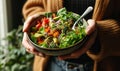 Woman holding a colorful bowl of salad with nuts.