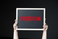 A woman holding a conceptual FREEDOM sign on violence