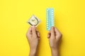 Woman holding condom and birth control pills on yellow background. Safe sex Royalty Free Stock Photo