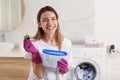 Woman holding container with laundry detergent capsules in bathroom Royalty Free Stock Photo