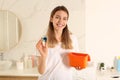 Woman holding container with laundry detergent capsules in bathroom Royalty Free Stock Photo
