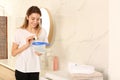 Woman holding container with laundry detergent capsules in bathroom Royalty Free Stock Photo