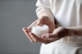 Woman holding cosmetic cream in open jar. Facial or hands skincare, moisturizing, beauty treatment concept. Generative AI