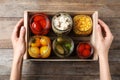 Woman holding crate with jars of pickled vegetables on table, top view Royalty Free Stock Photo