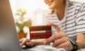 Woman holding a credit card and uses computer laptop to pay online. The concept of online shopping and payment.