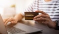 Woman holding a credit card and uses computer laptop to pay online. The concept of online shopping and payment.