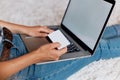 Woman holding credit card and working on a laptop Female using a laptop sitting on floor, Royalty Free Stock Photo