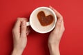 Woman holding cup of aromatic coffee with heart shaped decoration on red background, top view Royalty Free Stock Photo