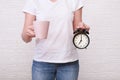 Woman holding a cup of coffee and alarm clock showing 7 am in hands, ready for work concept Royalty Free Stock Photo