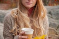 Woman holding cup of coffee in the hands outdoor. Beautiful woman drinking coffee in autumn park Royalty Free Stock Photo