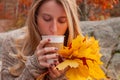 Woman holding cup of coffee in the hands outdoor. Beautiful woman drinking coffee in autumn park Royalty Free Stock Photo