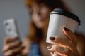 Woman holding a cup of coffee and looking at mobile phone Royalty Free Stock Photo