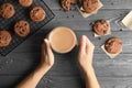 Woman holding cup of coffee near tasty chocolate chip cookies on wooden background Royalty Free Stock Photo