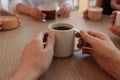 Woman holding cup of coffee spending time with friends in cafe, closeup Royalty Free Stock Photo