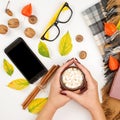 Woman holding cup of hot chocolate. Autumn composition with book, leaves, plaid