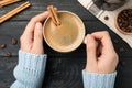 Woman holding cup of hot coffee with aromatic cinnamon at black wooden table, top view Royalty Free Stock Photo