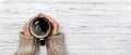 Woman holding cup of hot coffee on rustic wooden table, closeup photo of hands in warm sweater with mug, winter morning concept, t