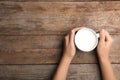 Woman holding cup of milk on wooden table, top view. Royalty Free Stock Photo