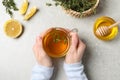Woman holding cup of tasty herbal tea with thyme at light grey table, top view Royalty Free Stock Photo