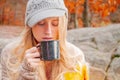 Woman holding cup of tea in the hands outdoor in autumn park Royalty Free Stock Photo