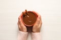 Woman holding cup of yummy hot chocolate with cinnamon at white wooden table, top view Royalty Free Stock Photo