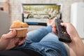 Woman Holding Cupcake And Remote Control In Hand