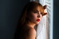 Woman holding the curtains open to look out of a large window at home. Positive and aspirational lifestyle. Royalty Free Stock Photo