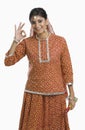 Woman holding a Dandiya at Navratri and making ok sign