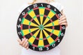 Woman holding a dart board in hands close up, aiming and targetting concept Royalty Free Stock Photo