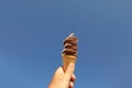 Woman holding delicious ice cream in wafer cone against blue sky, closeup Royalty Free Stock Photo