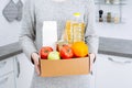 Woman holding delivering box with set of food stock for quarantine isolation period. Online food store and products delivery. Royalty Free Stock Photo