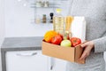 Woman holding delivering box with set of food stock for quarantine isolation period. Online food store and products delivery. Royalty Free Stock Photo