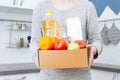 Woman holding delivering box with set of food stock for quarantine isolation period. Online food store and products delivery. Royalty Free Stock Photo