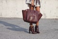 A woman holding a designer handbag and wearing booties