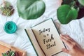 Woman holding a diary with inscription today is a fresh start with plants and succulents on white blanket. Homy