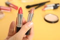 Woman holding different lipsticks over color table Royalty Free Stock Photo