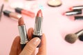 Woman holding different lipsticks over color table. Space for text Royalty Free Stock Photo